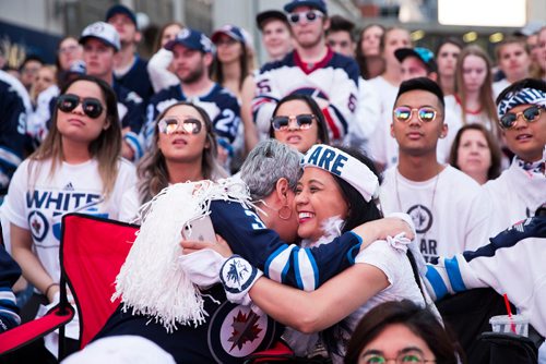 MIKAELA MACKENZIE / WINNIPEG FREE PRESS
Tina Quesnel (left) and Melanie IIag embrace after a Predators goal is almost overturned during a tense game at the whiteout street party in Winnipeg on Monday, May 7, 2018. 
Mikaela MacKenzie / Winnipeg Free Press 2018.