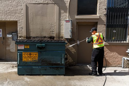 MIKE DEAL / WINNIPEG FREE PRESS
Chris Morgan with the Downtown BIZ washes the area around a dumpster in an alley south of Portage Avenue. 
180507 - Monday, May 07, 2018.
