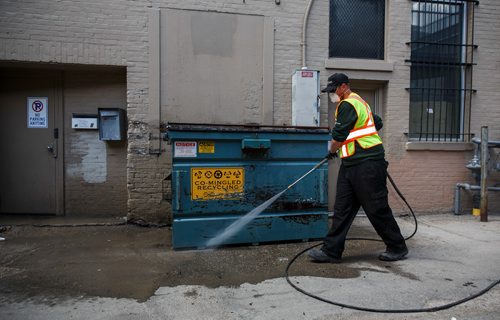 MIKE DEAL / WINNIPEG FREE PRESS
Chris Morgan with the Downtown BIZ washes the area around a dumpster in an alley south of Portage Avenue. 
180507 - Monday, May 07, 2018.