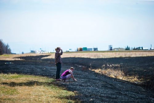 MIKAELA MACKENZIE / WINNIPEG FREE PRESS
Lucas Ottens (left) and Amanda Krouse take a look at the sooty mark left by a grass fire around the perimeter highway and Roblin Boulevard in Winnipeg on Tuesday, May 8, 2018. Community members say neighbourhood kids lit a bike on fire, and the fire rapidly spread.
Mikaela MacKenzie / Winnipeg Free Press 2018.