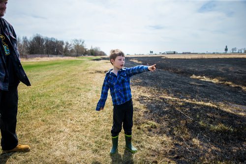 MIKAELA MACKENZIE / WINNIPEG FREE PRESS
Jayden Lepine, seven, points out the edges of the sooty mark the grass fire left around the perimeter highway and Roblin Boulevard in Winnipeg on Tuesday, May 8, 2018. Community members say neighbourhood kids lit the bike on fire, and the fire rapidly spread.
Mikaela MacKenzie / Winnipeg Free Press 2018.
