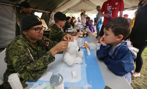 TREVOR HAGAN / WINNIPEG FREE PRESS
Rayden Mitchell, 5, patiently waits as Pte. Reetul Patel of 17 Field Ambulance patches up Polly the bear at the Teddy Bears Picnic in Assiniboine Park, Sunday, May 27, 2018.