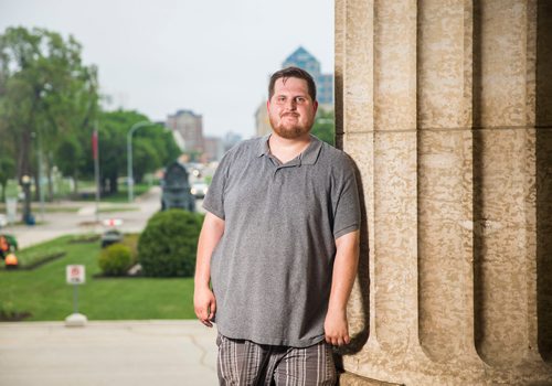 MIKAELA MACKENZIE / WINNIPEG FREE PRESS
Justin Luschinski, who is taking part in Pride this weekend, poses in front of the Manitoba Legislative Building in Winnipeg on Wednesday, May 30, 2018.  
Mikaela MacKenzie / Winnipeg Free Press 2018.