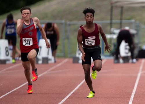 ANDREW RYAN / WINNIPEG FREE PRESS Trae Tomlinson, right, runs along side Graham Hutchison-Campbell from Glenlawn Collegiate. Tomlinson, a grade nine student from St. Paul's High School posted the fastest time in the Junior Varsity 100 metre sprint, beating senior varsity runners, during the MHSAA track and field event on June 8, 2018.