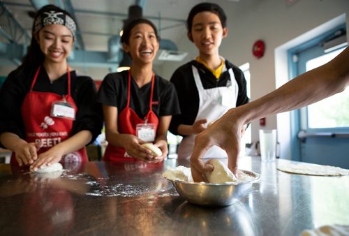 ANDREW RYAN / WINNIPEG FREE PRESS Kayla Umali, left, Erika Yazon, and Winzy Hinsunarin practice kneading pizza dough at the Food Justice Club on June 13, 2018. The Food Justice club at the NorWest Co-op Community Health is lead by chef Camille Metcalf.