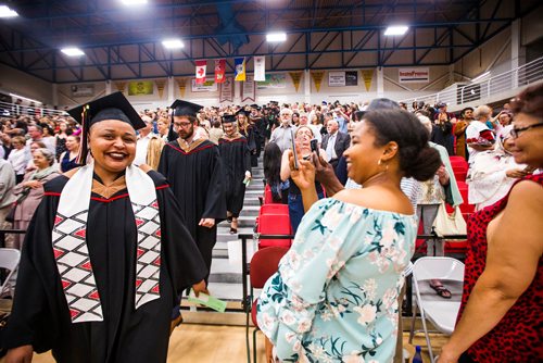 MIKAELA MACKENZIE / WINNIPEG FREE PRESS
Thomasena Downs-Mitchell, who is graduating with a bachelor of business administration, walks in as family takes pictures at the University of Winnipegs  2018 Spring Convocation ceremonies at the Duckworth Centre in Winnipeg on Friday, June 15, 2018. 
Mikaela MacKenzie / Winnipeg Free Press 2018.