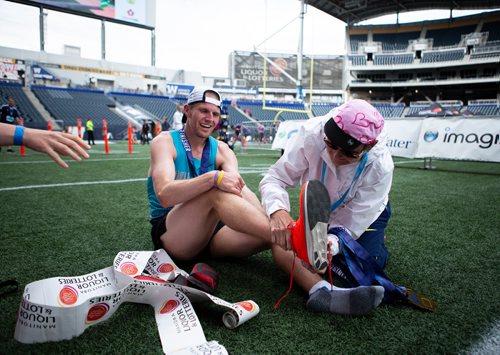 ANDREW RYAN / WINNIPEG FREE PRESS Manitoba men's marathon winner is helped with his shoes by Marylin "Mouse" Fraser near the finish line on June 17, 2018.