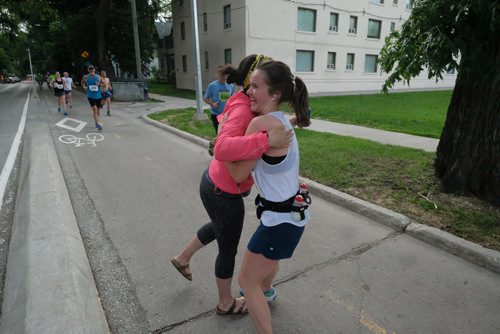 Daniel Crump / Winnipeg Free Press. Marathon supporter Janet Young (pink jacket) hugs a runner at the 40th Manitoba Marathon, Sunday, June 17, 2018.