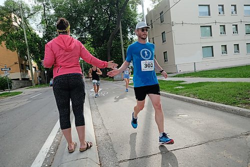 Daniel Crump / Winnipeg Free Press. Marathon supporter Janet Young gives full marathoner Jesse Cringan a fiver along the route. The 40th Manitoba Marathon, Sunday, June 17, 2018.