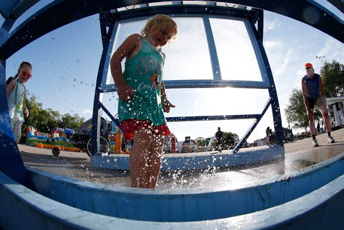 JOHN WOODS / WINNIPEG FREE PRESS
Kirsten Davis, 3, cools down while she plays in a water spray station as her grandpa Rick Gerbrandt and Ashley Strong, 2, look on at The Ex in Winnipeg Tuesday, June 19, 2018. The Ex is expecting great weather this year and even better attendance.