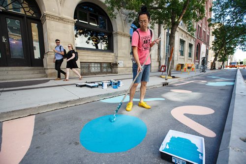 MIKE DEAL / WINNIPEG FREE PRESS
Artist Takashi Iwasaki paints designs in a stretch of the new protected bike lane on McDermot Wednesday afternoon.
180627 - Wednesday, June 27, 2018.