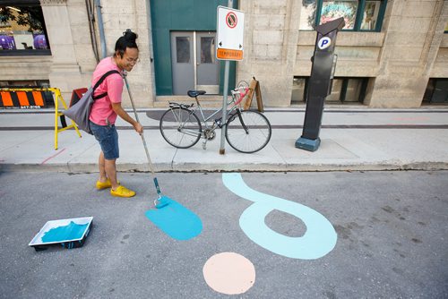 MIKE DEAL / WINNIPEG FREE PRESS
Artist Takashi Iwasaki paints designs in a stretch of the new protected bike lane on McDermot Wednesday afternoon.
180627 - Wednesday, June 27, 2018.