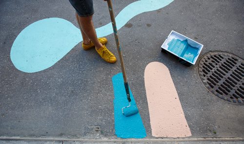 MIKE DEAL / WINNIPEG FREE PRESS
Artist Takashi Iwasaki paints designs in a stretch of the new protected bike lane on McDermot Wednesday afternoon.
180627 - Wednesday, June 27, 2018.