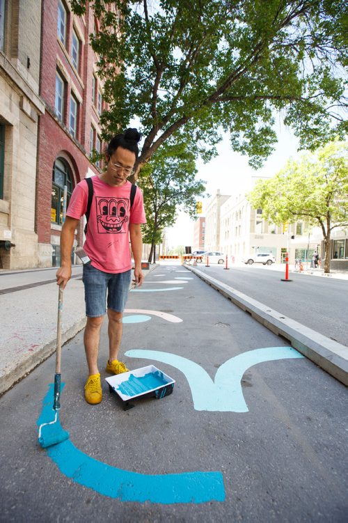 MIKE DEAL / WINNIPEG FREE PRESS
Artist Takashi Iwasaki paints designs in a stretch of the new protected bike lane on McDermot Wednesday afternoon.
180627 - Wednesday, June 27, 2018.