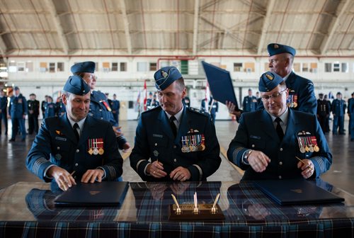 ANDREW RYAN / WINNIPEG FREE PRESS Newly appointed 17 Wing Commander Colonel J.P.E. Charron, left, slides his signed document transferring command of 17 Wing to Brigadier General David Cochrane. Colonel Andy Cook, far right, relinquished command of the squadron on June 28, 2018.