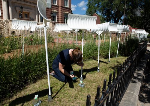 ANDREW RYAN / WINNIPEG FREE PRESS Meaghan Hunter puts the finishing touches on Shovel Garden in front of La Maison des Artiste Visuels. The installation is part of a series put on by The Forks called Cool Gardens. Shovel Garden features nearly 130 white shovels reminding Winnipeggers of their winter temperatures which, at times, rival Mars. Shot on July 5, 2018.
