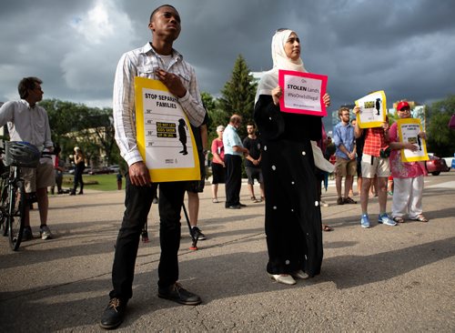 ANDREW RYAN / WINNIPEG FREE PRESS Ugonna Chigbo, left, from Nigeria, and Pakistani Nosheen Umar stand together at a protest in support of refugees suffering through boarder politics in North America on July 11, 2018.