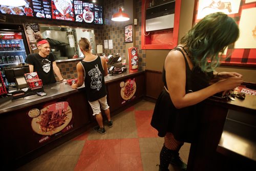 JOHN WOODS / WINNIPEG FREE PRESS
Keith Mercier, kitchen manager at Smokes Poutinerie, serves up some poutine to Reid Marshall and Jez Nepinak in Winnipeg Friday, July 13, 2018. This is part of the 24hourproject

