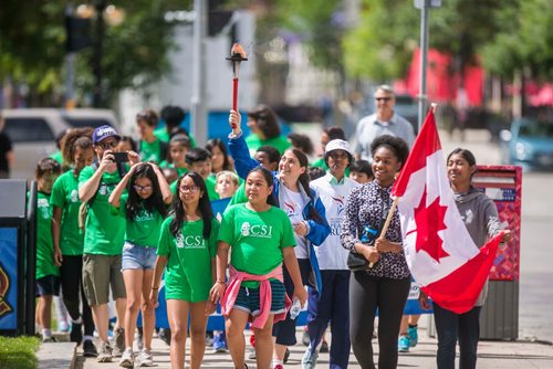 MIKAELA MACKENZIE / WINNIPEG FREE PRESS
Music teacher Purnakama Rajna holds the torch and leads students from Ecole Victoria Albert School in a peace run at City Hall in Winnipeg on Monday, July 16, 2018. 
Mikaela MacKenzie / Winnipeg Free Press 2018.