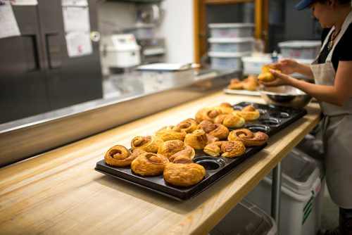 MIKAELA MACKENZIE / WINNIPEG FREE PRESS
Brittney Albanese, assistant manager, dips cinnamon buns into sugar at Pennyloaf bakery in Winnipeg on Friday, July 13, 2018. 24hourproject
Mikaela MacKenzie / Winnipeg Free Press 2018.