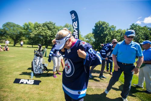 MIKAELA MACKENZIE / WINNIPEG FREE PRESS
Five-time LPGA tournament winner Brooke Henderson tries on a signed Jets jersey she received as a gift after doing a clinic with the Future Pros Program at the St. Charles Country Club in Winnipeg on Tuesday, July 17, 2018. 
Mikaela MacKenzie / Winnipeg Free Press 2018.