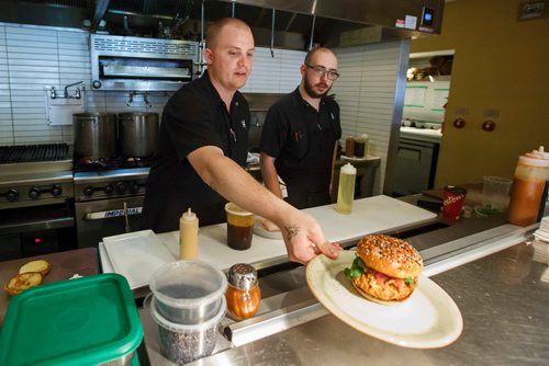 MIKE DEAL / WINNIPEG FREE PRESS
The Merchant Kitchen restaurant at 314 Donald Street.
Executive chef Jesse Friesen serves up their burger for this falls Burger Week for the social media photographer while opening line cook Ian Shapira looks on.
The kitchen prepares food from their updated menu for a social media promotion including a sneak peak of their burger week creation which will debut at the beginning of September.
180713 - Friday, July 13, 2018.
24hourproject
