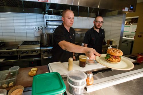 MIKE DEAL / WINNIPEG FREE PRESS
The Merchant Kitchen restaurant at 314 Donald Street.
Executive chef Jesse Friesen serves up their burger for this falls Burger Week for the social media photographer while opening line cook Ian Shapira looks on.
The kitchen prepares food from their updated menu for a social media promotion including a sneak peak of their burger week creation which will debut at the beginning of September.
180713 - Friday, July 13, 2018.
24hourproject