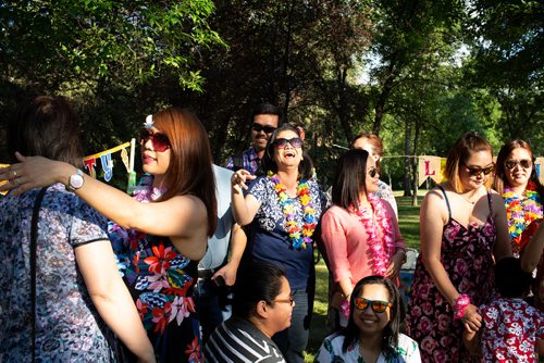 ANDREW RYAN / WINNIPEG FREE PRESS Gina Arroza (second from left, in blue and white shirt) beams after being surprised with a 50th birthday bash in Kildonan Park Friday, July 13, 2018. Her co-workers, including Antonia Guevarra (far left, wearing watch, preparing to hug party guest), Argen Daypal (second from right, in pink shirt) and Hazel Legaspi (right, in strappy flowered dress), helped organize the soirée. 
FOR STACEY THIDRICKSONS 7 P.M. GATHERING IN KILDONAN PARK, 24-HOUR FOOD FOR THOUGHT PROJECT 24hourproject