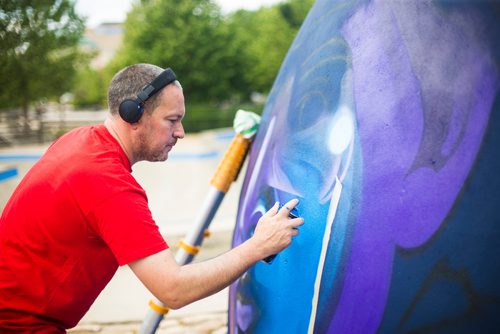 MIKAELA MACKENZIE / WINNIPEG FREE PRESS
London-based artist Mr Cenz works on a mural on the outside of the skate bowl at the Forks in Winnipeg on Friday, July 20, 2018. 
Winnipeg Free Press 2018.