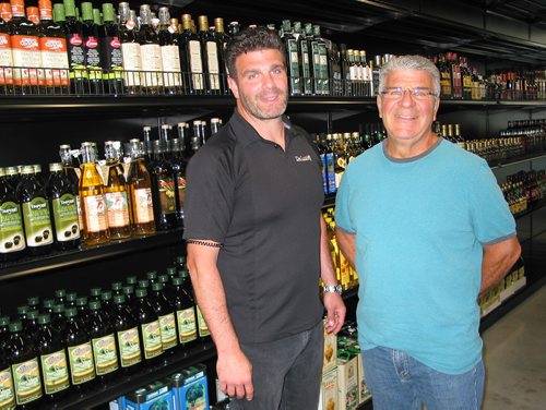 Canstar Community News July 18, 2018 - (From left) Marco De Luca and his father Peter stand next to shelves holding the many varieties of oils and vinegars in the reatil section of the family's new location at 66 South Landing in the RM of Macdonald. (ANDREA GEARY/CANSTAR COMMUNITY NEWS)