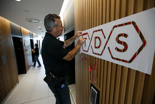 MIKE DEAL / WINNIPEG FREE PRESS
Larry Neudorf installs the TDS law firm logo in the elevator lobby on the 17th floor of their new offices at True North Square Monday morning.
180723 - Monday, July 23, 2018.