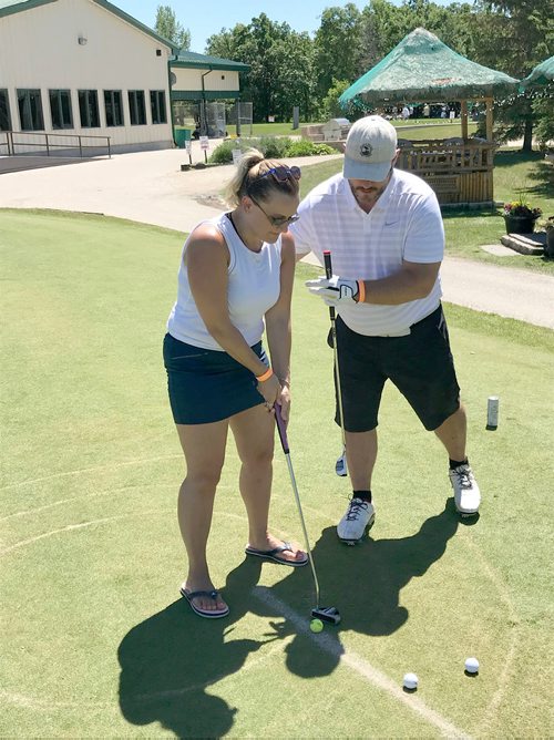 SUBMITTED PHOTO

Joanna Cheliah receives guidance from her partner Mike Watts to try to hit a ball while wearing eyewear to obstruct her vision at the La Salle Insurance and Travel Ltd. Charity Golf Tournament held at Kingswood Golf & Country Club on June 28, 2018 to raise funds for the Society for Manitobans with Disabilities (SMD) Assistive Technology Program. (See Social Page)