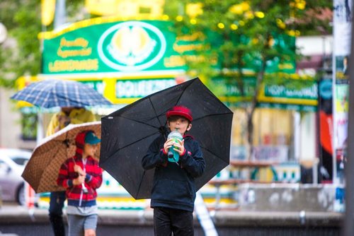 MIKAELA MACKENZIE / WINNIPEG FREE PRESS
Hayden Thiem walks through Old Market Square with a lemonade and an umbrella on a rainy day at the Fringe Festival in Winnipeg on Wednesday, July 25, 2018. 
Winnipeg Free Press 2018.