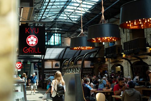 ANDREW RYAN / WINNIPEG FREE PRES Patrons of the The Forks Atrium walk past the Kyu Grill store front sign on July 26, 2018.