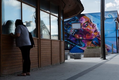 ANDREW RYAN / WINNIPEG FREE PRES A woman looks at her reflection near the recently unveiled mural painted onto the side of The Ndinawe Youth Resource Centre by UK based artist Mr Cenz on July 26, 2018. The mural was commissioned by  the Graffiti Gallery and was gifted to the centre in honour of the community of families and survivors of Missing and Murdered Indigenous Women and Girls and to Ndinawemaaganag Endaawaad Inc. as a thank you for the work that they do in relation to the cause.