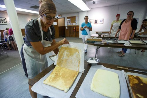 MIKE DEAL / WINNIPEG FREE PRESS
Alenia Howell pulls off the parchment after flipping the sponge for the lemon torte in the basement of the Our Lady of Lourdes church at 95 MacDonald Ave. where volunteers are baking huge lemon tortes for the Slovenian pavilion which makes all their own food for Folklorama.
180721 - Saturday, July 21, 2018.