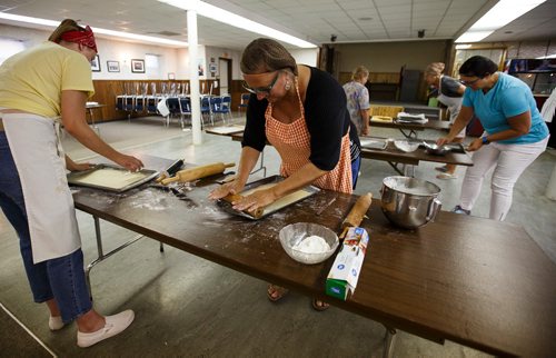 MIKE DEAL / WINNIPEG FREE PRESS
Diane Schuster (centre) and her daughter, Olivia (left) roll out the dough for the Honey biscuit layer of the lemon torte in the basement of the Our Lady of Lourdes church at 95 MacDonald Ave. where volunteers are baking huge lemon tortes for the Slovenian pavilion which makes all their own food for Folklorama.
180721 - Saturday, July 21, 2018.