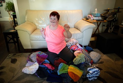 ANDREW RYAN / WINNIPEG FREE PRESS Solveig Meinhardt lives with Down syndrome and is knitting hats for Koats for Kids. The 16-year-old learned to knit in November of 2017 and has knitted nearly 190 hats since then. She in pictured with about 75 of her hats on the family's living room floor on August 1, 2018.
