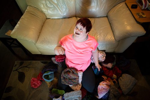 ANDREW RYAN / WINNIPEG FREE PRESS Solveig Meinhardt lives with Down syndrome and is knitting hats for Koats for Kids. The 16-year-old learned to knit in November of 2017 and has knitted nearly 190 hats since then. She in pictured with about 75 of her hats on the family's living room floor on August 1, 2018.
