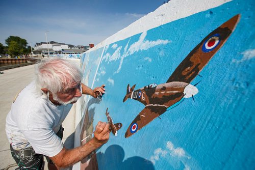 MIKE DEAL / WINNIPEG FREE PRESS
Painter Millard Vance Barteaux retouches one of the murals on the harbour front wall in Gimli Thursday morning.
180802 - Thursday, August 02, 2018.