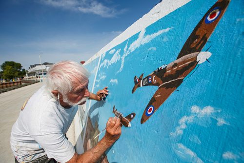 MIKE DEAL / WINNIPEG FREE PRESS
Painter Millard Vance Barteaux retouches one of the murals on the harbour front wall in Gimli Thursday morning.
180802 - Thursday, August 02, 2018.