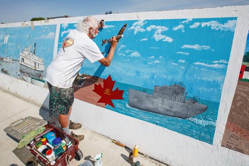 MIKE DEAL / WINNIPEG FREE PRESS
Painter Millard Vance Barteaux retouches one of the murals on the harbour front wall in Gimli Thursday morning.
180802 - Thursday, August 02, 2018.