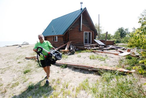 PHIL HOSSACK / WINNIPEG FREE PRESS - Arnold Asham walks away with a pressure washer from his log cottage which was lifted off its foundation and a sunroom/porch ripped off in Friday's tornado. Looters were chased off the beach shortly after the storm. See story. - August 8, 2018