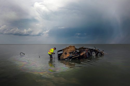 PHIL HOSSACK / WINNIPEG FREE PRESS - Surrounded by an oily sheen while a squall blows across lake Manitoba behind him, Daniel Cottyn attaches a tow line to the wreckage of a camper in Lake Manitoba at the Margaret Bruce Beach and campground Tuesday. A tornado ripped through the Alonsa Manitoba area Friday. See story. - August 7, 2018  
