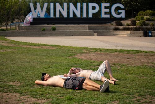 ANDREW RYAN / WINNIPEG FREE PRESS Thomas Gregson, right, and Abram Dyck lay sweaty in the sun after throwing around a frisbee in The Forks park on August 11, 2018.