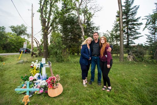 MIKAELA MACKENZIE / WINNIPEG FREE PRESS
Brenda (left), John, and Hannah Harris stand by the makeshift memorial at Donald road and highway nine, where Ben Harris was killed in a hit-and-run, in the R.M. of St. Andrews on Monday, Aug. 13, 2018. 
Winnipeg Free Press 2018.