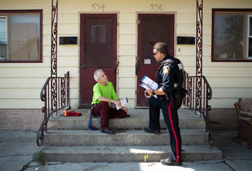ANDREW RYAN / WINNIPEG FREE PRESS Albert Collette, a resident of the William Whyte neighbourhood for 8 years, listens to officer Martin Boileau talk about the Make the Right Call campaign part of the Winnipeg Police's attempt to increase their positive presence in the city's north end neighbourhood on Manitoba Ave. on August 15, 2018.
