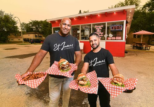 Mike Sudoma / Winnipeg Free Press
From Left: Owner Ravi Ramberran and GM Sanjay Sewpaul show off their burger creations outside of their Ness Ave. restaurant Thursday morning. August 16, 2018. St. James Burger & Chip Co.