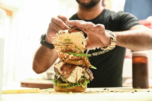 Mike Sudoma / Winnipeg Free Press
Samjay Sewpaul trying to keep a freshly made "17 Wing Burger contained. August 16, 2018. St. James Burger & Chip Co.