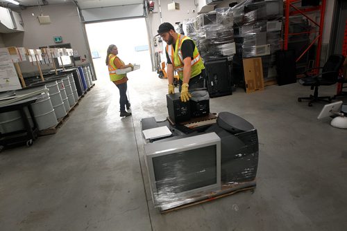 PHIL HOSSACK / WINNIPEG FREE PRESS -  A worker packs electronics onto a pallet while another carries florescent light fixtures to another bin at the city's newest 4R Recycling Depot on Panet Road Thursday. See Jill Wilson's story. - August 15, 2018
